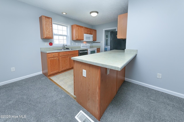 kitchen featuring visible vents, baseboards, light countertops, white appliances, and a sink