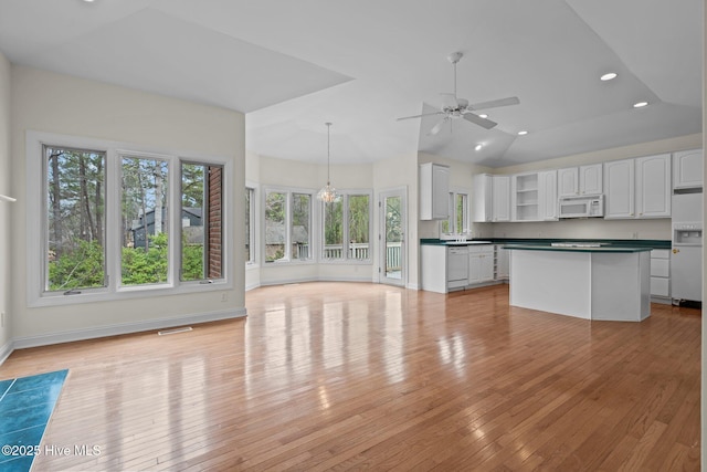 kitchen featuring white appliances, open shelves, white cabinets, dark countertops, and ceiling fan with notable chandelier