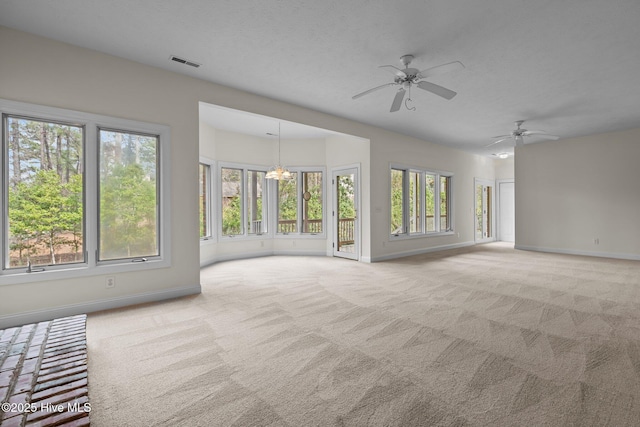 unfurnished living room featuring carpet flooring, ceiling fan with notable chandelier, visible vents, and baseboards