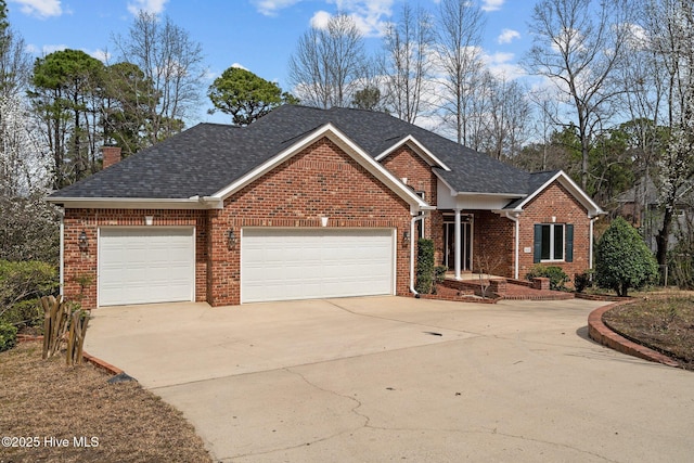 view of front of property with driveway, an attached garage, a shingled roof, brick siding, and a chimney