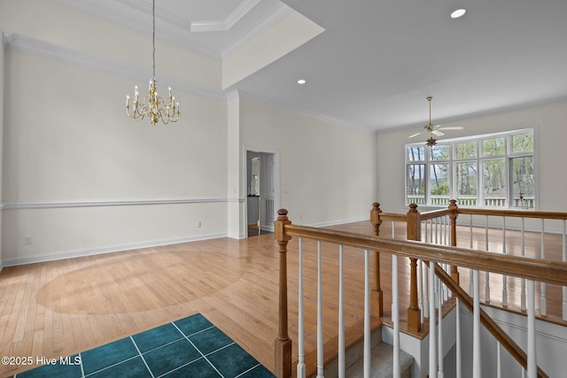 corridor with an upstairs landing, an inviting chandelier, wood finished floors, and crown molding