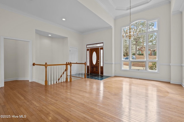 foyer entrance with hardwood / wood-style flooring, a notable chandelier, baseboards, and ornamental molding