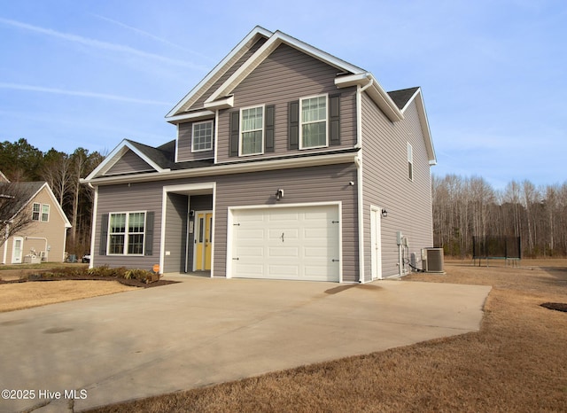 traditional-style house with central air condition unit, an attached garage, and driveway