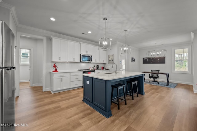 kitchen with white cabinets, appliances with stainless steel finishes, ornamental molding, and a sink