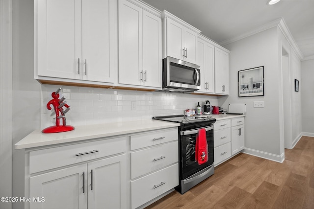 kitchen with light wood-type flooring, tasteful backsplash, appliances with stainless steel finishes, white cabinets, and crown molding