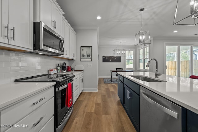 kitchen featuring ornamental molding, a sink, tasteful backsplash, stainless steel appliances, and light countertops