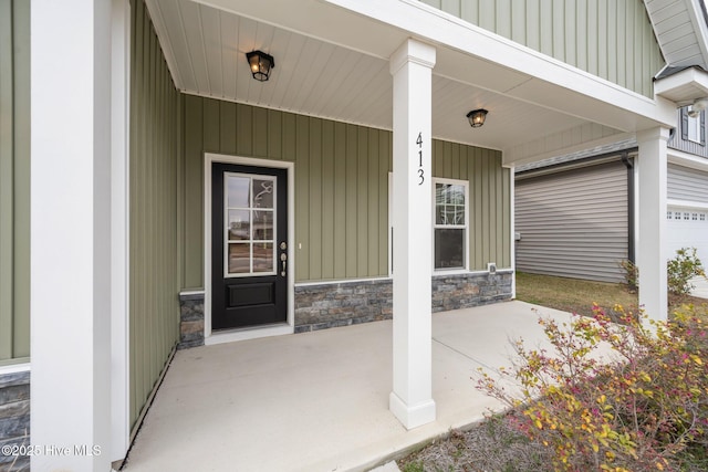 entrance to property featuring a porch, stone siding, and board and batten siding