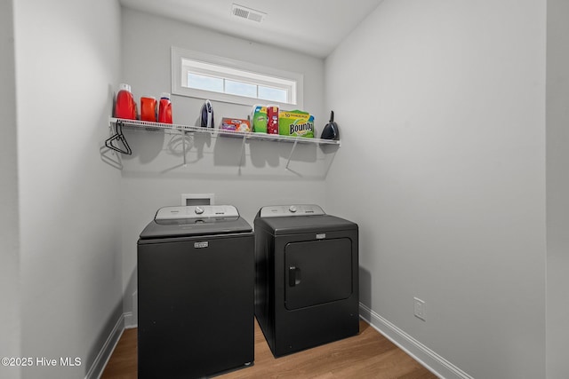 laundry area featuring visible vents, baseboards, laundry area, wood finished floors, and washer and dryer