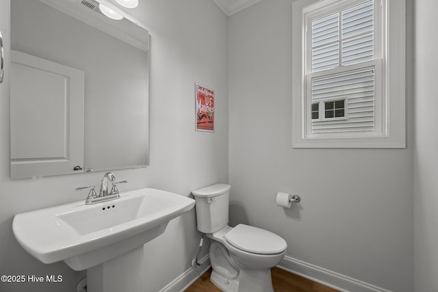 bathroom featuring toilet, wood finished floors, baseboards, and a sink