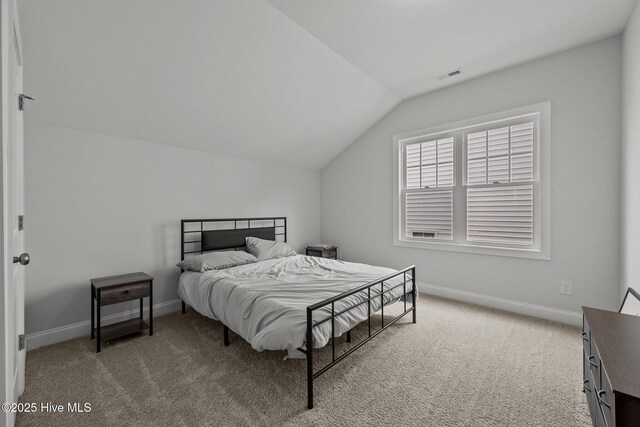 bedroom featuring visible vents, light colored carpet, baseboards, and lofted ceiling