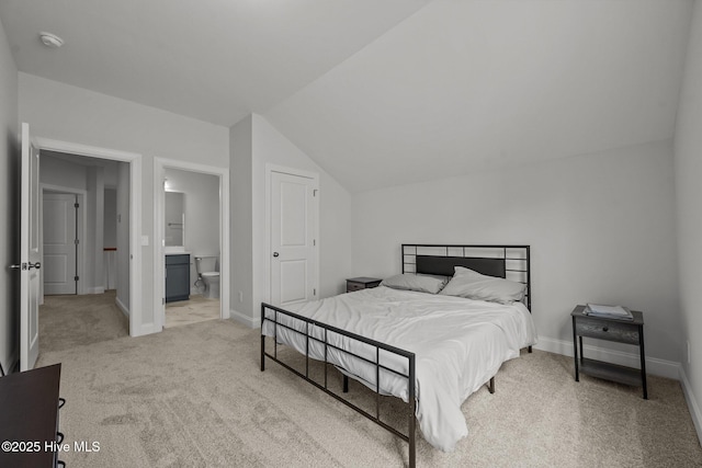 carpeted bedroom featuring vaulted ceiling, baseboards, and ensuite bathroom