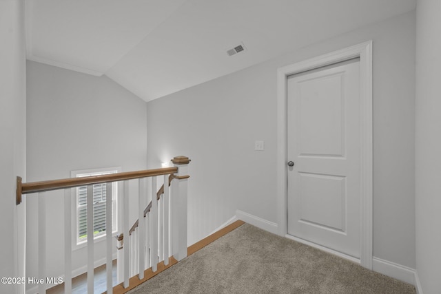 hallway with an upstairs landing, visible vents, baseboards, and lofted ceiling