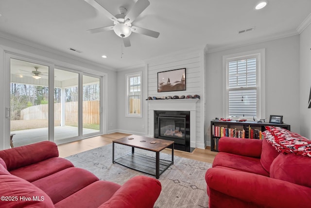 living room featuring crown molding, wood finished floors, a ceiling fan, and visible vents