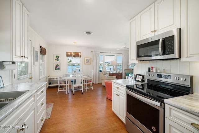 kitchen featuring visible vents, white cabinetry, stainless steel appliances, light wood-style floors, and light countertops