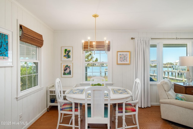 dining room with a water view, a notable chandelier, and wood finished floors