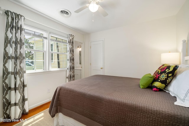 bedroom with a ceiling fan, visible vents, wood finished floors, and baseboards