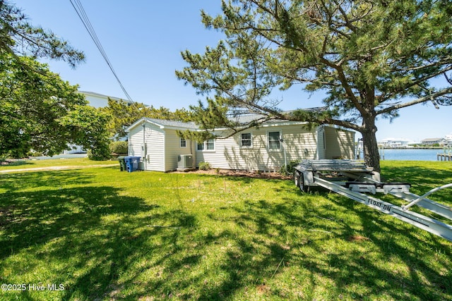 exterior space with a lawn, a water view, and central AC