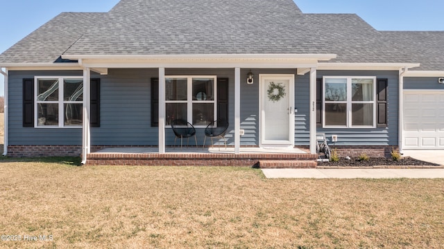 view of front facade with a front yard, covered porch, and roof with shingles