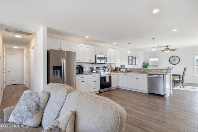 kitchen featuring visible vents, open floor plan, stainless steel appliances, a peninsula, and white cabinets