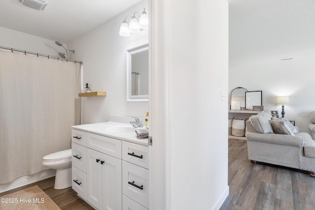 bathroom with vanity, a shower with shower curtain, wood finished floors, visible vents, and toilet