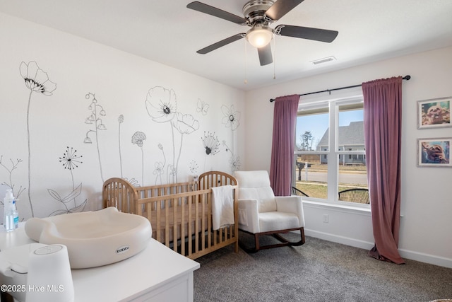 bedroom with visible vents, a crib, a ceiling fan, carpet flooring, and baseboards