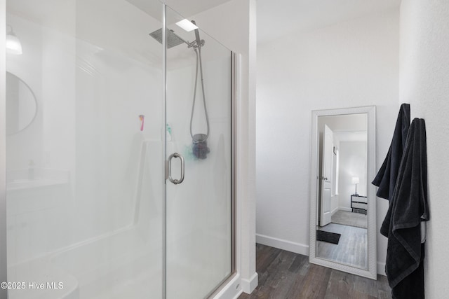 bathroom featuring wood finished floors, a stall shower, and baseboards