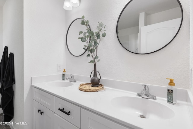 bathroom with double vanity, a textured wall, and a sink