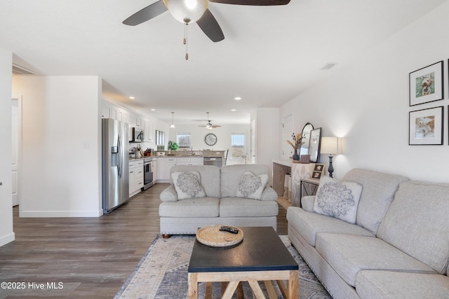 living room featuring wood finished floors, a ceiling fan, visible vents, baseboards, and recessed lighting