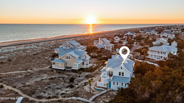 aerial view at dusk with a residential view, a water view, and a beach view