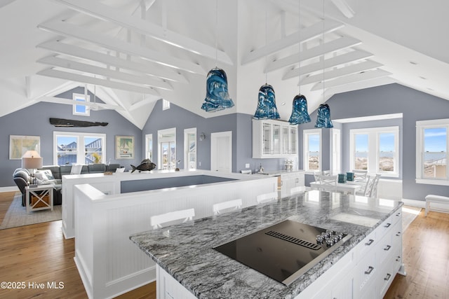 kitchen with a kitchen island, wood finished floors, open floor plan, white cabinets, and black electric stovetop