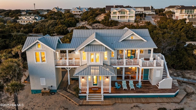 back of house with a standing seam roof, a balcony, and metal roof