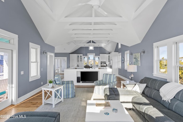 living room featuring light wood finished floors, beam ceiling, baseboards, and ceiling fan