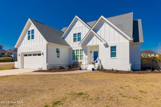 modern inspired farmhouse with brick siding, board and batten siding, a front yard, driveway, and an attached garage