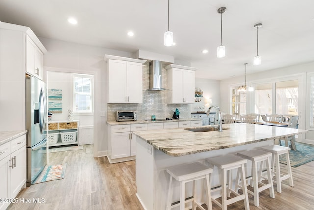 111 E Magens Ct, Cedar Point, NC 28584 - kitchen featuring wall chimney exhaust hood, stainless steel fridge, black electric cooktop, a breakfast bar, and light wood-type flooring