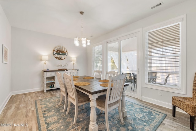 dining area featuring baseboards, visible vents, a chandelier, and light wood-type flooring