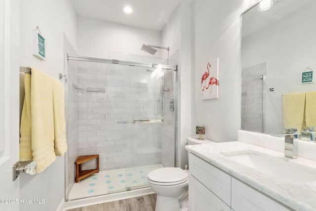 bathroom with toilet, a stall shower, vanity, and wood finished floors