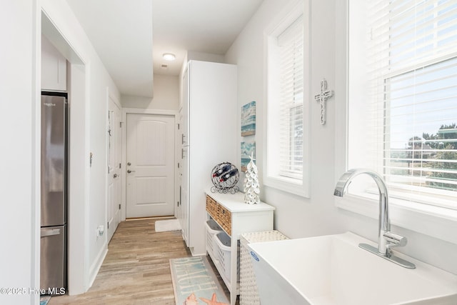 interior space featuring a healthy amount of sunlight, freestanding refrigerator, light wood-style floors, and a sink