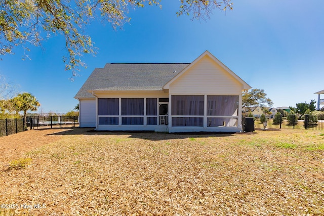 rear view of house featuring a lawn, a shingled roof, a fenced backyard, and a sunroom