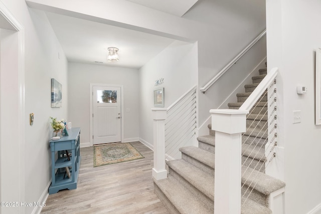 foyer entrance featuring stairway, baseboards, and wood finished floors