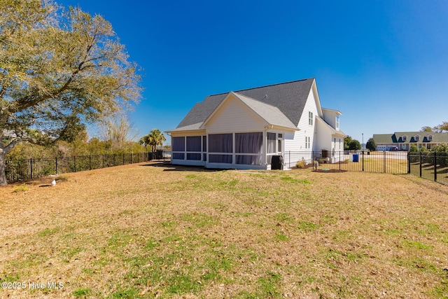 rear view of property featuring a lawn, roof with shingles, a fenced backyard, and a sunroom