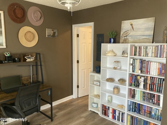 office area with a textured ceiling, baseboards, and wood finished floors