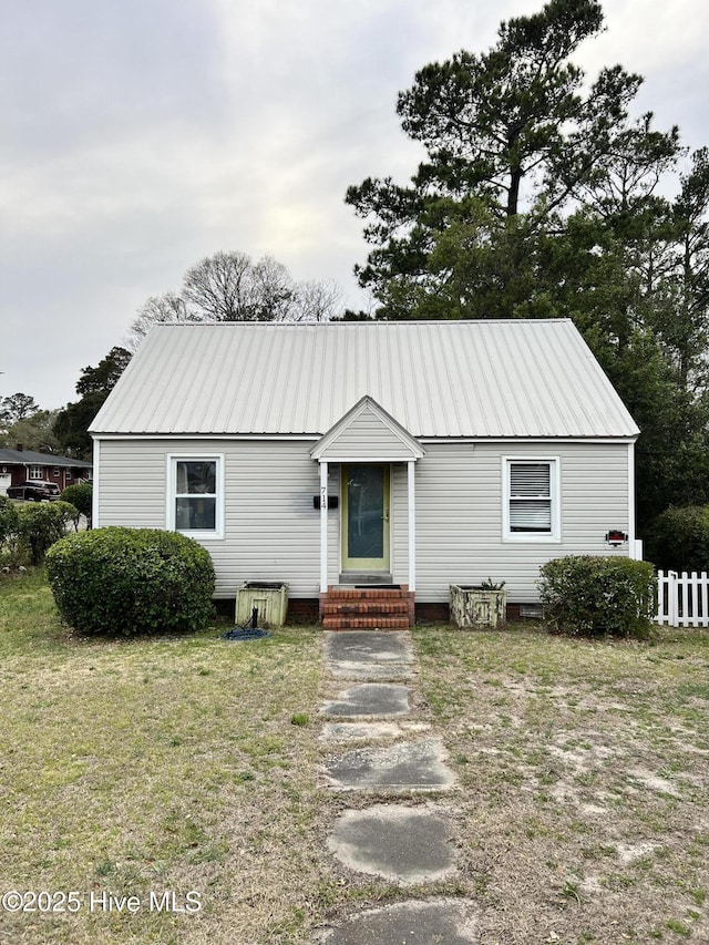 view of front facade with entry steps, a front lawn, fence, and metal roof