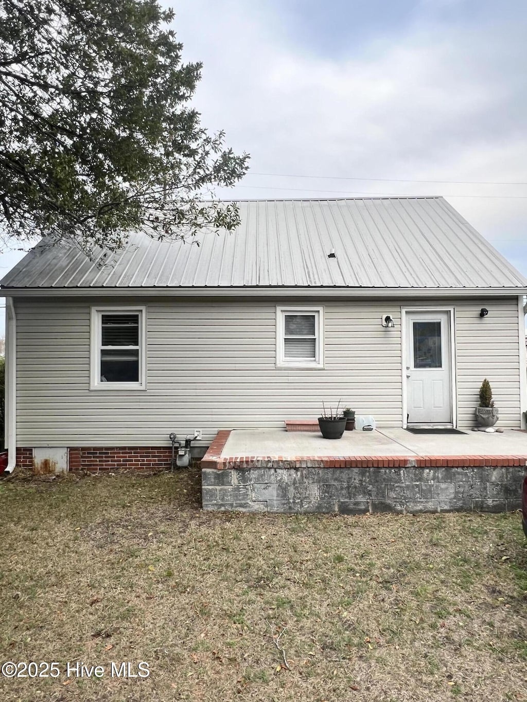 rear view of house featuring metal roof, a yard, and a patio area