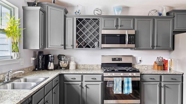 kitchen featuring plenty of natural light, gray cabinetry, stainless steel appliances, and a sink