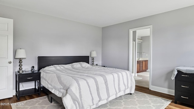 bedroom with connected bathroom, baseboards, and wood finished floors