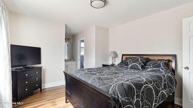 bedroom featuring wood finished floors, baseboards, and connected bathroom