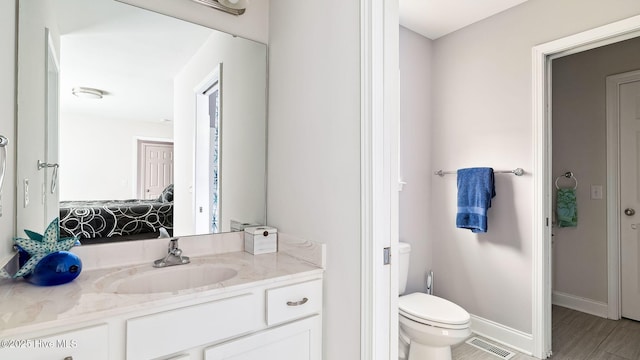 ensuite bathroom featuring vanity, baseboards, visible vents, toilet, and connected bathroom