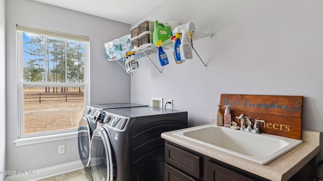 laundry area with cabinet space, washing machine and dryer, baseboards, and a sink