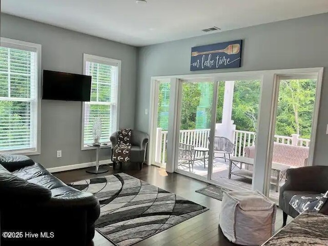 living room featuring visible vents, baseboards, and wood finished floors