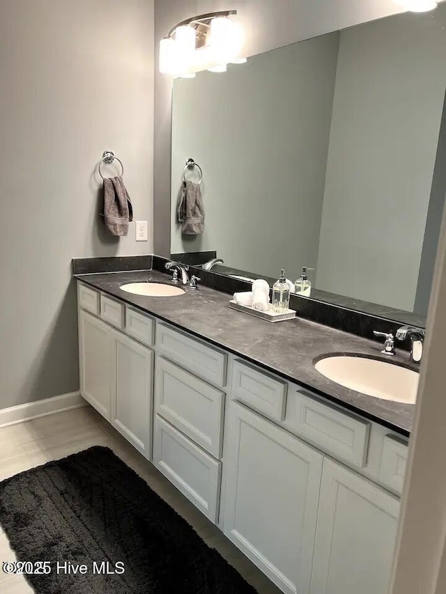 bathroom featuring double vanity, baseboards, and a sink